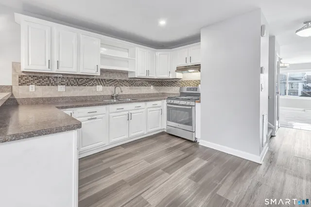 a kitchen with stainless steel appliances granite countertop a sink and cabinets with wooden floor