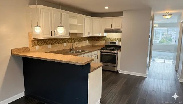 a kitchen with a sink a stove cabinets and wooden floor