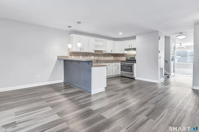 a kitchen with kitchen island granite countertop a sink cabinets and wooden floor