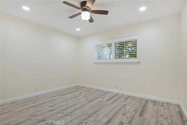 an empty room with wooden floor fan and windows