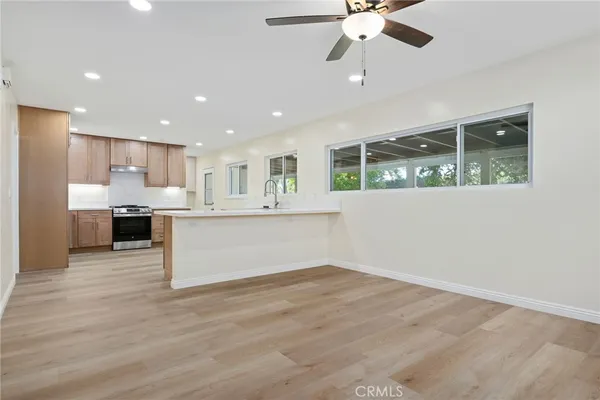 a view of kitchen with kitchen island stainless steel appliances wooden floor cabinets and a window