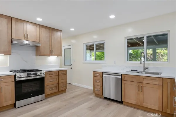 a kitchen with stainless steel appliances granite countertop a stove a sink and a wooden floors
