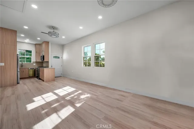 a view of an empty room with a window and wooden floor