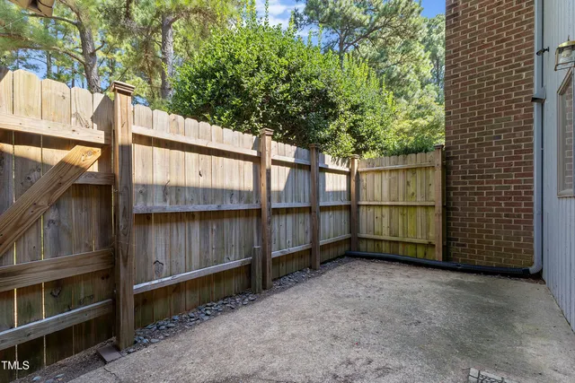 a view of backyard with large trees and wooden fence
