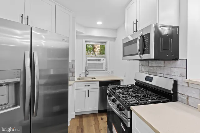 a kitchen with stainless steel appliances granite countertop a refrigerator a sink a stove with wooden cabinets