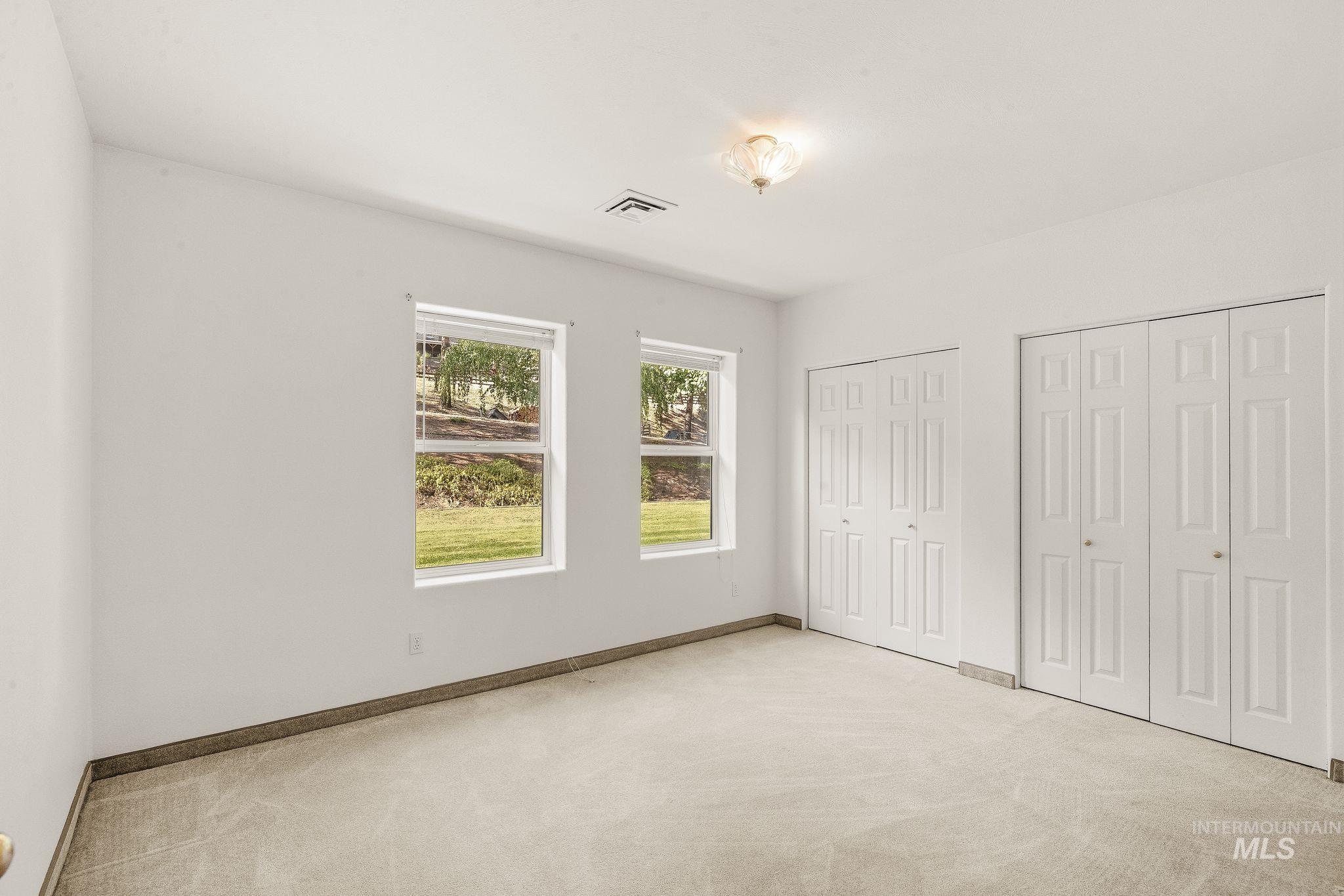 1091 Cedar Ridge Road Kendrick, ID 83537 - Photo 35 of 48 Spacious room featuring neutral carpeting, two large windows, two sets of bi-fold closets, and a ceiling-mounted light fixture
