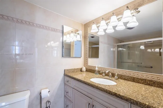 a bathroom with a granite countertop sink mirror and shower