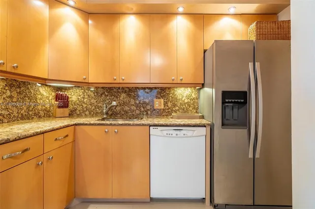 a kitchen with stainless steel appliances granite countertop a refrigerator and a sink