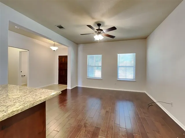 a view of an empty room with window and wooden floor