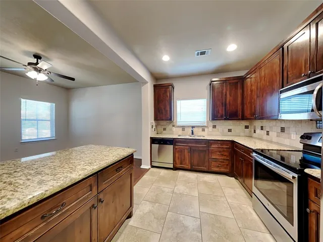 a large kitchen with granite countertop a stove sink and cabinets