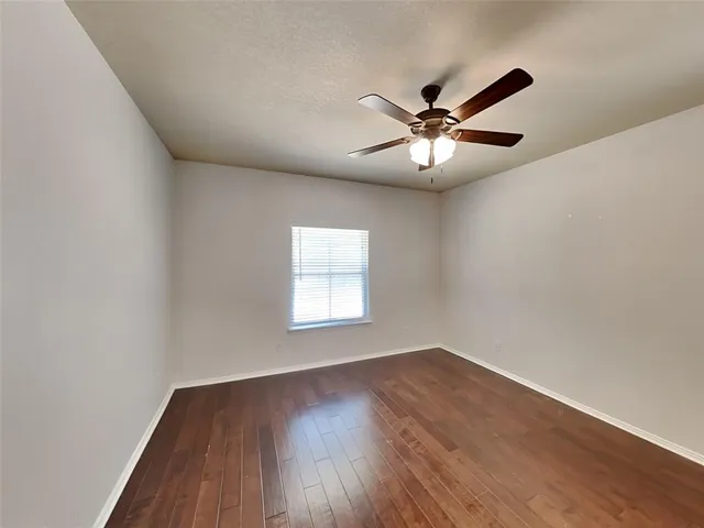 a view of a livingroom with a fan a ceiling fan and wooden floor