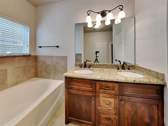 a bathroom with a granite countertop sink a mirror and a bathtub
