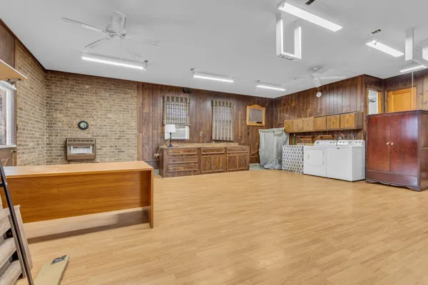 a view of an empty room with wooden floor and a kitchen