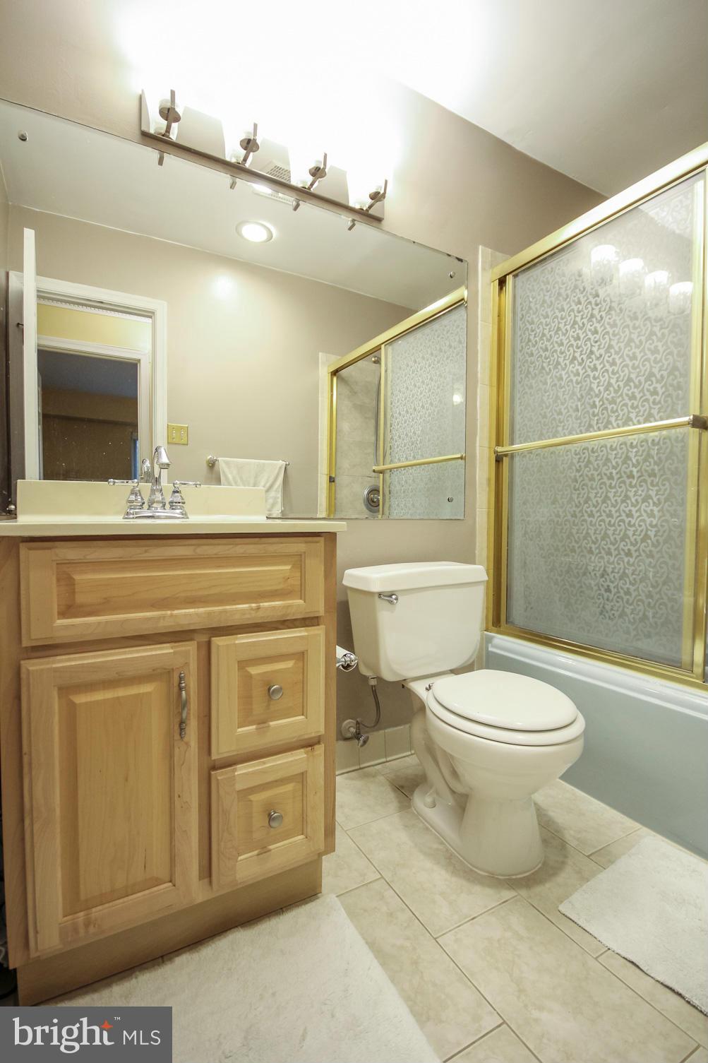 6155 Edsall Road, Unit 6155 Alexandria, VA 22304 - Photo 17 of 29 a bathroom with a granite countertop toilet a sink a mirror and shower