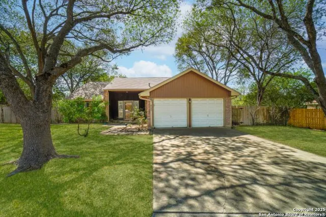 a front view of a house with a garden and trees