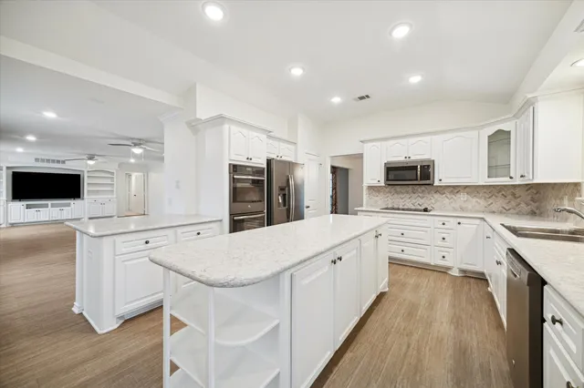 a kitchen with granite countertop a sink stove refrigerator and cabinets