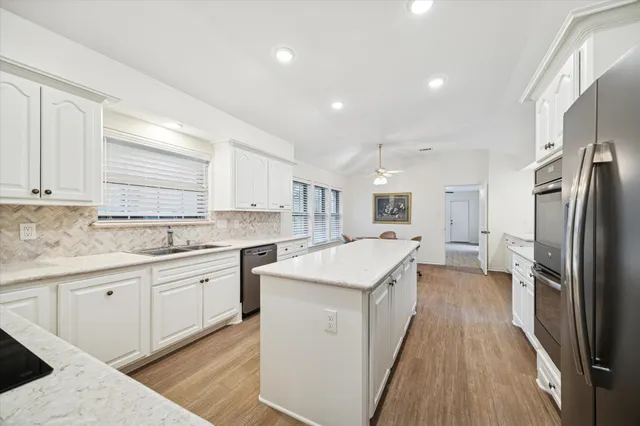 an empty room with a chandelier fan and windows