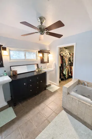a spacious bathroom with a tub sink and mirror