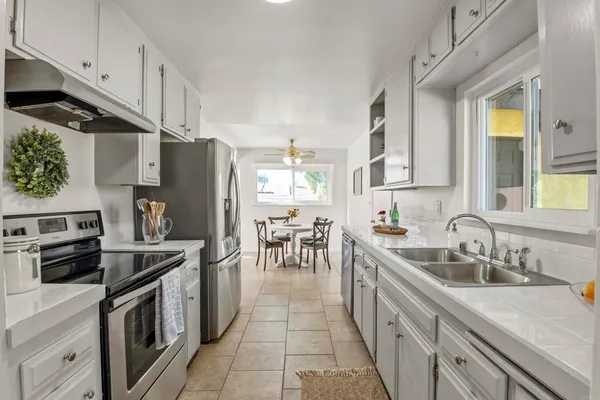 a kitchen with stainless steel appliances a sink stove refrigerator and a window