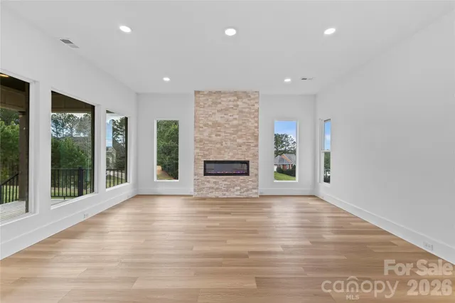 an empty room with wooden floor fireplace and windows