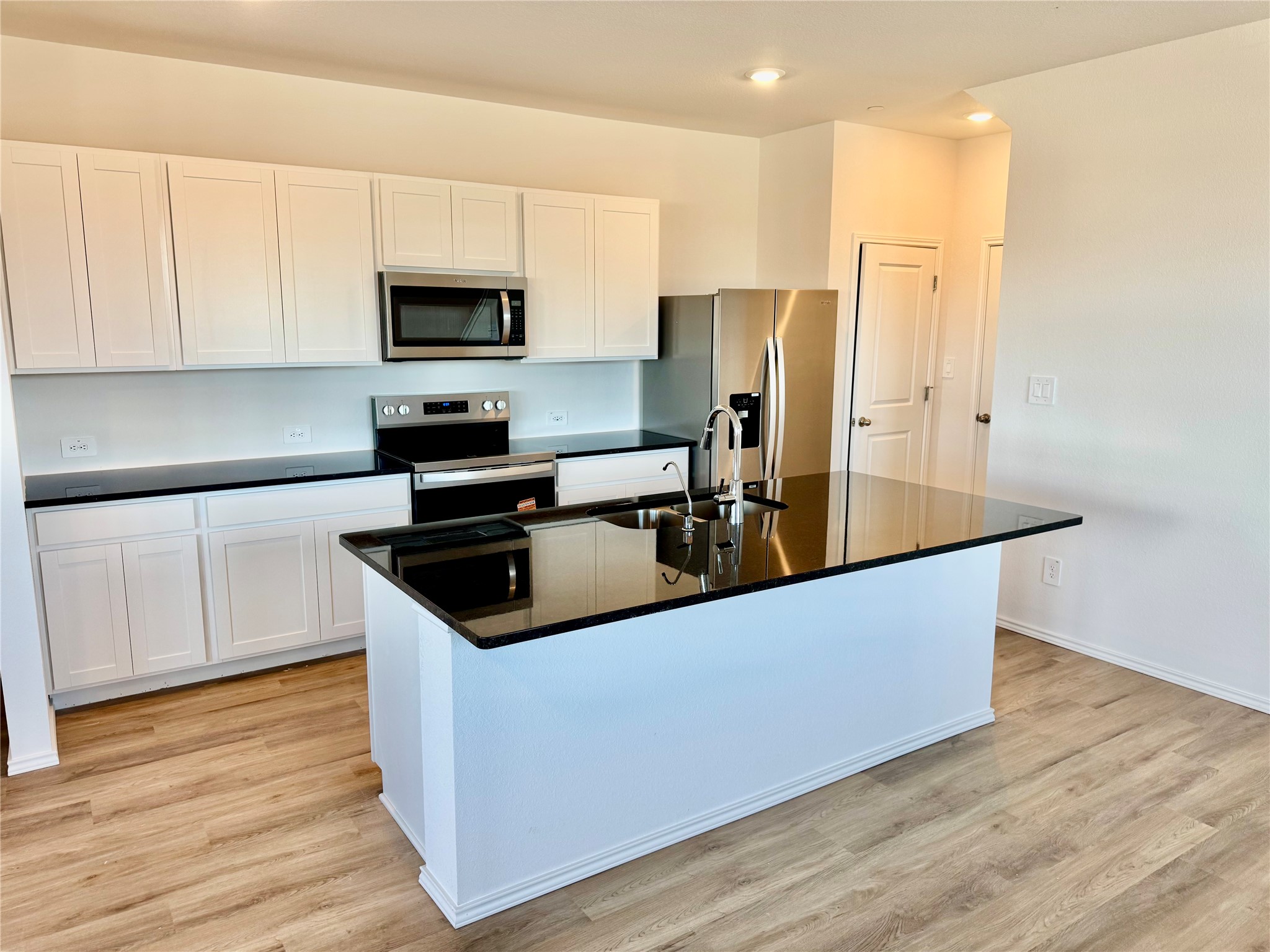 105 Calcite Road, Unit 1 Kyle, TX 78640 - Photo 2 of 7 Kitchen with white cabinetry, stainless steel appliances, an island with sink, light wood-style floors, and recessed lighting