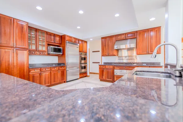 a view of a kitchen with kitchen island granite countertop a refrigerator and a sink