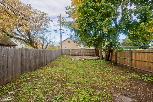 a view of a backyard with wooden fence and a large tree