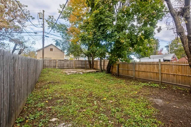 a view of a backyard with wooden fence and a large tree