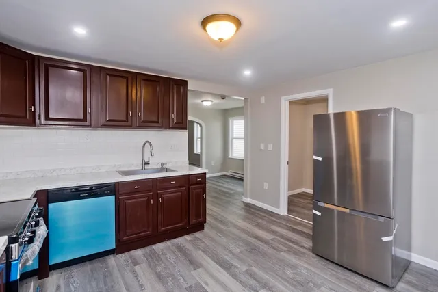 a kitchen with stainless steel appliances granite countertop a refrigerator a sink dishwasher and wooden cabinets with wooden floor