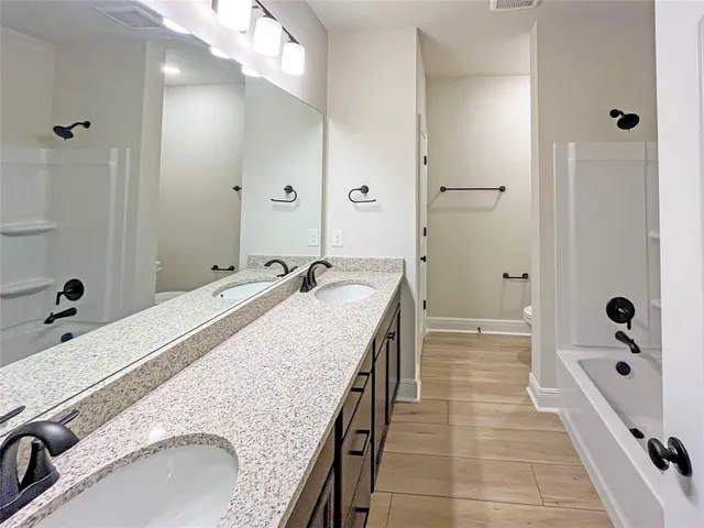 a spacious bathroom with a granite countertop sink a mirror and shower