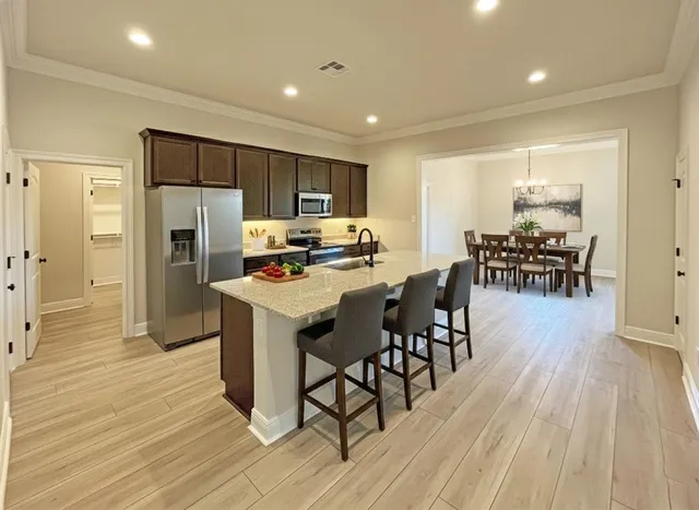 a kitchen with stainless steel appliances a dining table chairs stove refrigerator and wooden floor