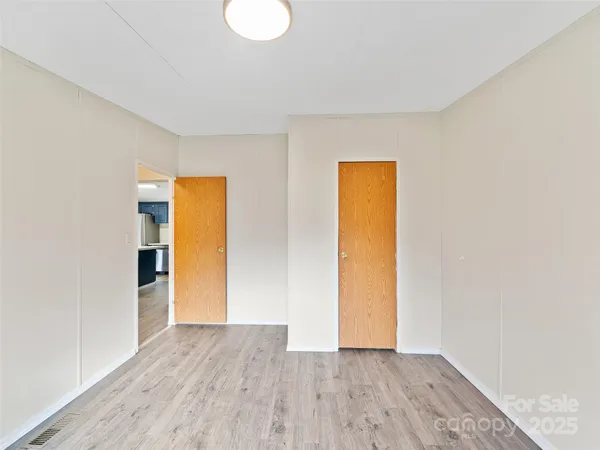 a view of an empty room with wooden floor and closet