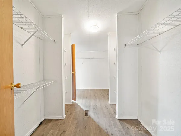 a view of a hallway with wooden floor and cabinet