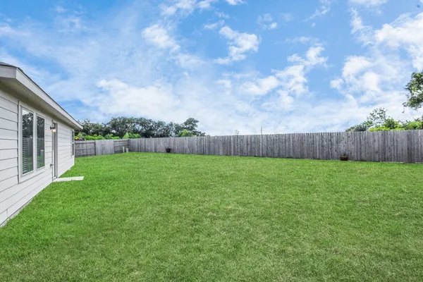 a view of a house next to a big yard and large trees