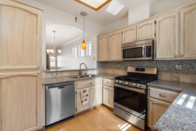 a kitchen with stainless steel appliances granite countertop a stove a sink and a microwave