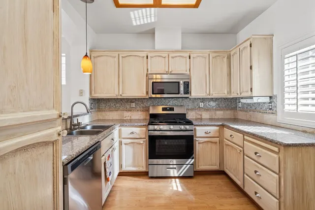 a kitchen with stainless steel appliances granite countertop white cabinets a sink and a stove