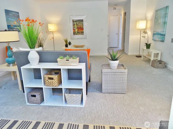 a living room with furniture a potted plant and kitchen view