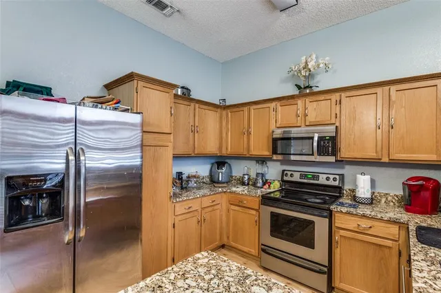 a kitchen with stainless steel appliances granite countertop a refrigerator a stove and a sink