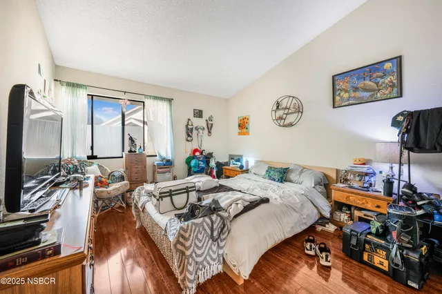 a bed room with a bed a computer on a desk and a book shelf