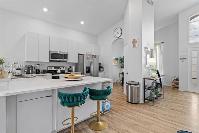 a kitchen with stainless steel appliances a dining table chairs stove refrigerator and cabinets