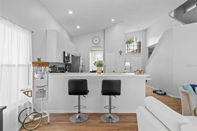 a kitchen with stainless steel appliances granite countertop a refrigerator a stove a oven with white cabinets and wooden floor