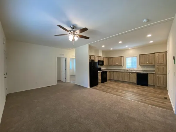 a view of an empty room with kitchen view and a kitchen