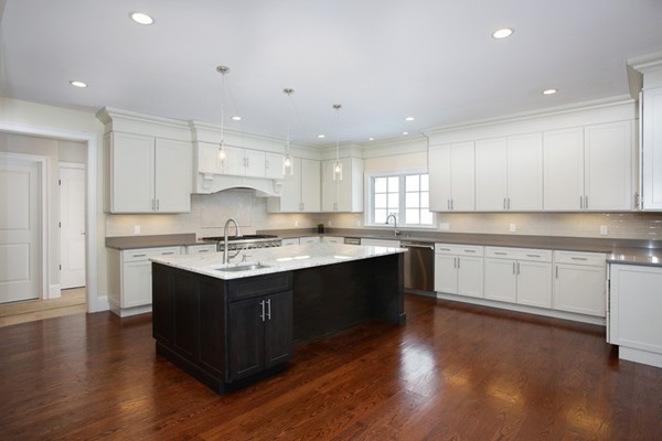 81 Wayne Road Newton, MA 02459 - Photo 3 of 7 a large kitchen with granite countertop a white stove top oven and white cabinets with wooden floor
