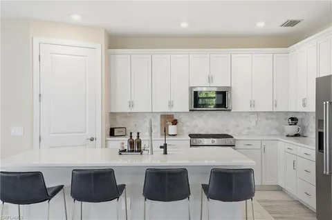 a kitchen with stainless steel appliances granite countertop a stove a sink a microwave and white cabinets