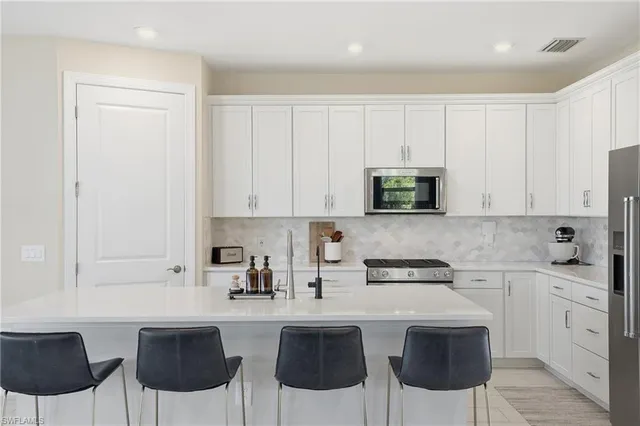 a kitchen with stainless steel appliances granite countertop a stove a sink a microwave and white cabinets