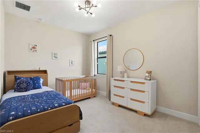 a bedroom with a bed a chandelier and dresser