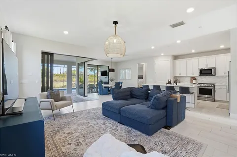 a living room with furniture kitchen view and a large window