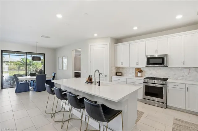 a kitchen with stainless steel appliances a stove a sink a microwave a dining table and chairs