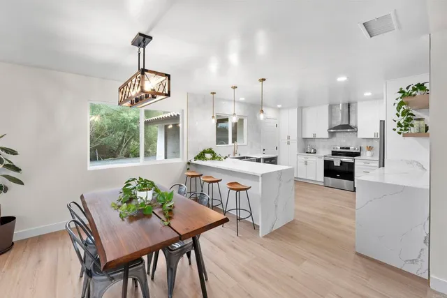 a kitchen with stainless steel appliances kitchen island granite countertop a table chairs and a living room
