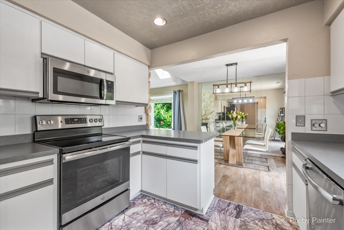 1085 Oswego Road Naperville, IL 60540 - Photo 11 of 31 a kitchen with stainless steel appliances kitchen island granite countertop a stove top oven a sink dishwasher a dining table and chairs with wooden floor